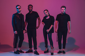 Image showing Group of young multiethnic musicians created band, dancing in neon light on pink background