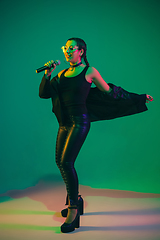 Image showing Caucasian female singer portrait isolated on green studio background in neon light