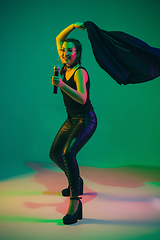 Image showing Caucasian female singer portrait isolated on green studio background in neon light