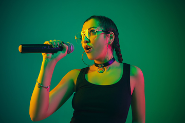 Image showing Caucasian female singer portrait isolated on green studio background in neon light