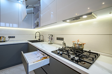 Image showing Luxury white and dark grey modern kitchen interior with open drawer