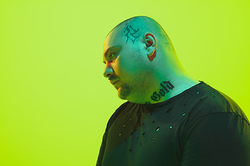 Image showing Portrait of a guy with colorful neon light on green background