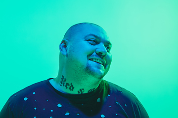 Image showing Portrait of a guy with colorful neon light on green background