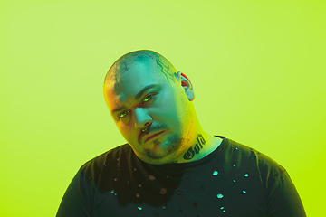 Image showing Portrait of a guy with colorful neon light on green background