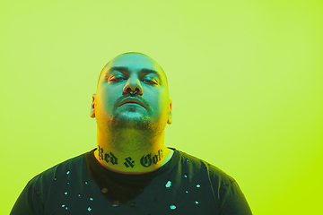 Image showing Portrait of a guy with colorful neon light on green background