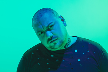 Image showing Portrait of a guy with colorful neon light on green background