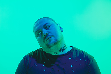 Image showing Portrait of a guy with colorful neon light on green background