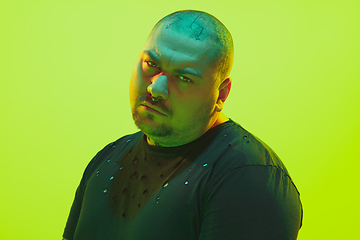 Image showing Portrait of a guy with colorful neon light on green background