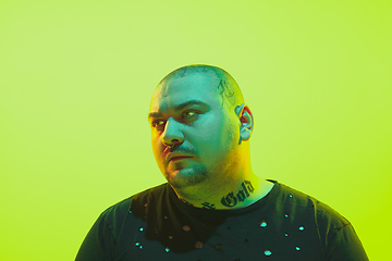 Image showing Portrait of a guy with colorful neon light on green background