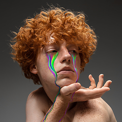 Image showing Portrait of young beautiful man with neon, fluid tears from eyes. Concept of fashion and beauty, emotions and feelings, modern design