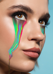 Image showing Portrait of young beautiful woman with neon, fluid tears from eyes. Concept of fashion and beauty, emotions and feelings, modern design