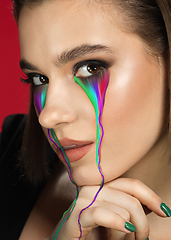 Image showing Portrait of young beautiful woman with neon, fluid tears from eyes. Concept of fashion and beauty, emotions and feelings, modern design