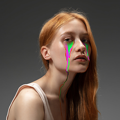 Image showing Portrait of young beautiful woman with neon, fluid tears from eyes. Concept of fashion and beauty, emotions and feelings, modern design