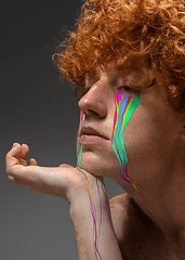 Image showing Portrait of young beautiful man with neon, fluid tears from eyes. Concept of fashion and beauty, emotions and feelings, modern design