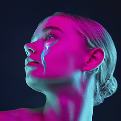 Image showing Portrait of young beautiful woman with neon, fluid tears from eyes. Concept of fashion and beauty, emotions and feelings, modern design