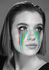 Image showing Portrait of young beautiful woman with neon, fluid tears from eyes. Concept of fashion and beauty, emotions and feelings, modern design