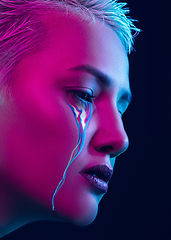 Image showing Portrait of young beautiful woman with neon, fluid tears from eyes. Concept of fashion and beauty, emotions and feelings, modern design