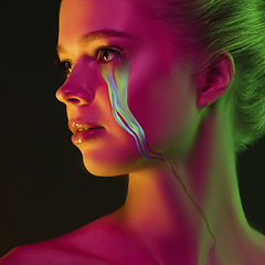 Image showing Portrait of young beautiful woman with neon, fluid tears from eyes. Concept of fashion and beauty, emotions and feelings, modern design