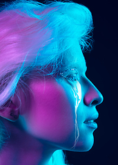 Image showing Portrait of young beautiful woman with neon, fluid tears from eyes. Concept of fashion and beauty, emotions and feelings, modern design