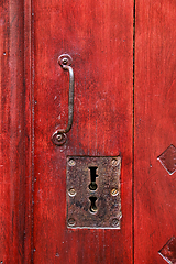 Image showing Vintage red wooden door with metallic handle and keyholes