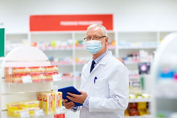 Image showing old apothecary in mask with tablet pc at pharmacy