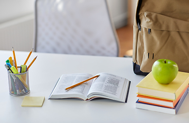 Image showing books, apple and school supplies on table at home