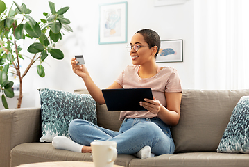 Image showing happy woman with tablet pc and credit card at home