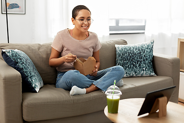 Image showing african woman with tablet pc eating takeaway food