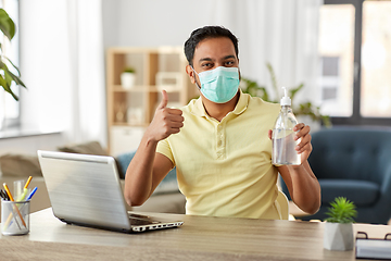 Image showing man in mask with hand sanitizer at home office