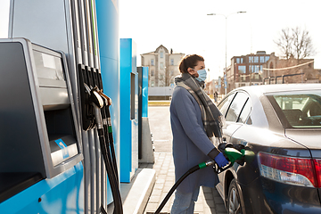 Image showing woman in mask filling car at gas station