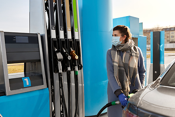 Image showing woman in mask filling car at gas station