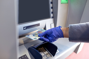 Image showing hand in medical glove with money at atm machine