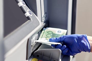 Image showing hand in medical glove with money at atm machine