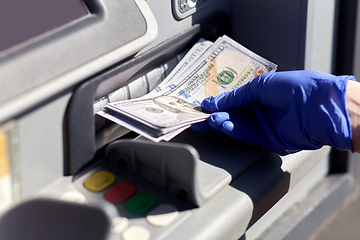 Image showing hand in medical glove with money at atm machine