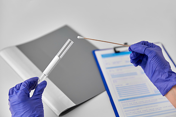 Image showing hands in gloves holding test tube and cotton swab