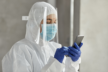 Image showing doctor in protective wear with smartphone