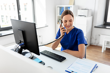 Image showing doctor with computer calling on phone at hospital