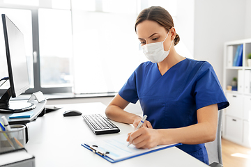 Image showing doctor or nurse in mask with clipboard at hospital