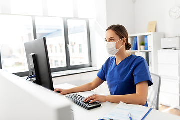 Image showing doctor or nurse in mask with computer at hospital