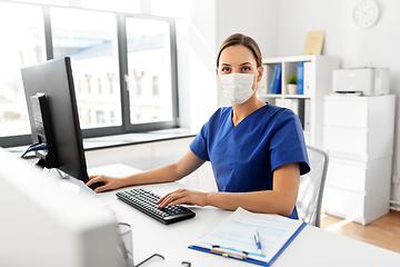 Image showing doctor or nurse in mask with computer at hospital