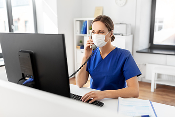 Image showing doctor with computer calling on phone at hospital