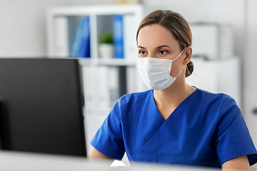 Image showing doctor or nurse in mask with computer at hospital