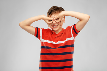 Image showing happy smiling boy looking through finger glasses