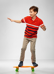 Image showing smiling boy riding on short skateboard