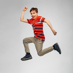 Image showing happy smiling young boy jumping or running in air