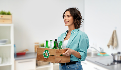 Image showing smiling young woman sorting glass waste at home