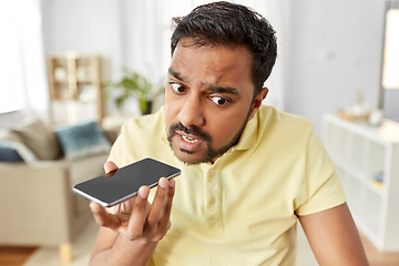 Image showing angry man recording voice on smartphone at home