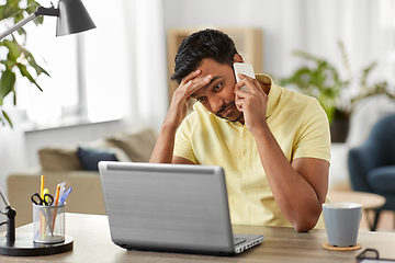 Image showing indian man with laptop calling on phone at home