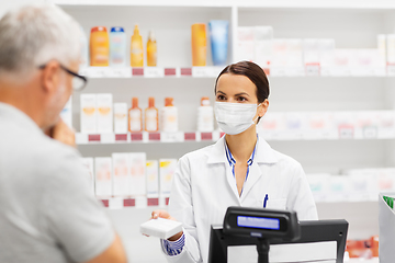 Image showing apothecary in mask showing drug to man at pharmacy