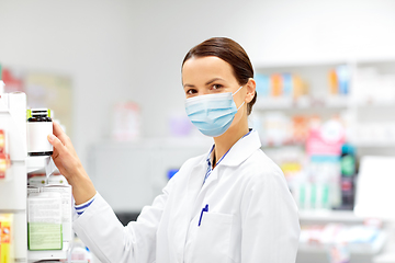 Image showing female apothecary in mask with drug at pharmacy